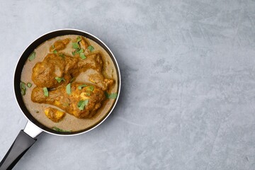 Delicious chicken with curry sauce on grey table, top view. Space for text