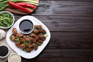 Tasty soy sauce, roasted meat and ingredients on wooden table, flat lay. Space for text