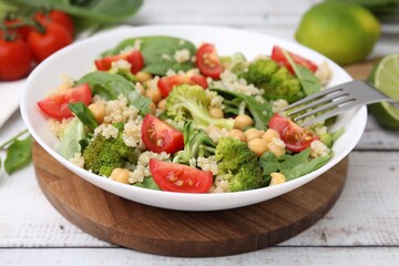 Healthy meal. Tasty salad with quinoa, chickpeas and vegetables on white wooden table, closeup