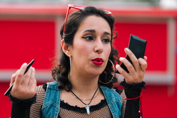 bella mujer latina maquillándose  y mirándose al espejo para sesión de fotos al aire libre...