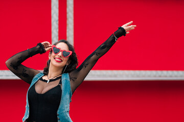 retrato de bella mujer latina sonriendo con maquillaje jugando con sus lentes rojos al aire libre...