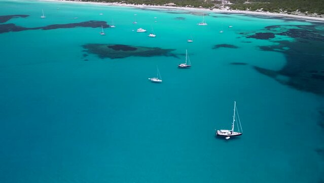 A group of sailboats on the water at Es Tranc beach mallorca, aerial view, turquoise and cyan, place with many yachts, mediterranean coastline, caribbean feeling, tropical style, travel location