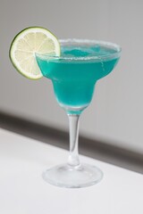 Glass of cocktail decorated with lemon at bar counter background.