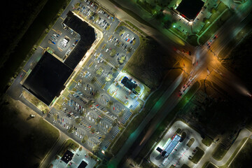 Aerial night view of many cars parked on parking lot with lines and markings for parking places and directions. Place for vehicles in front of a grocery mall store © bilanol