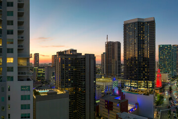 View from above of brightly illuminated skyscraper buildings in downtown district of Miami Brickell in Florida, USA at night. American megapolis with business financial district