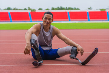 Elated Asian speed runner, donned in two prosthetic running blades, sits on the stadium track, taking a breather after a fulfilling speed running practice session - Powered by Adobe