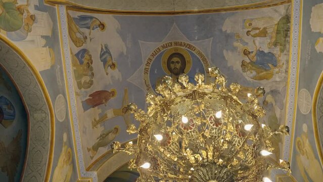 Christian iconography on ceiling frescos over ornate golden chandelier