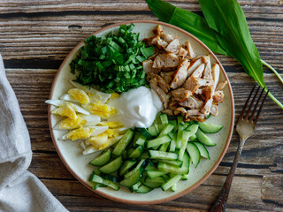 Homemade healthy spring salad with chicken breast, cucumbers, eggs and wild garlic ramson. Proper nutrition. Dietary menu. Flat lay. Top view