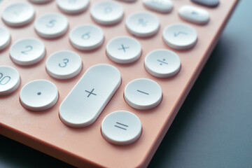 close up modern peach colour pastel calculator and white button on blue background, business and finance accounting concept