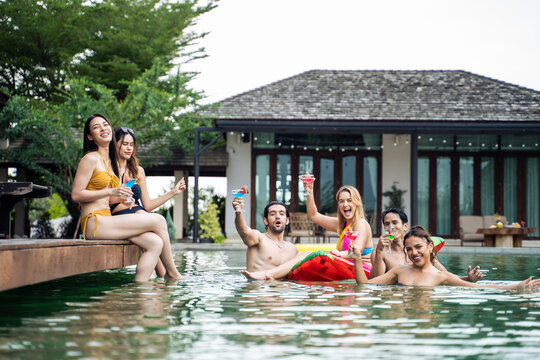 Group of diverse friend drinking alcohol, having a pool party together. 