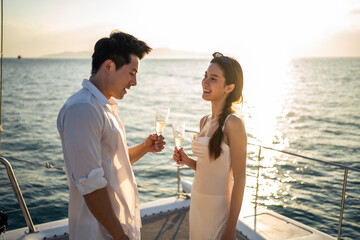 Asian beautiful couple drinking champagne while having party in yacht. 