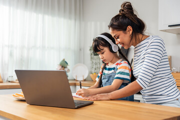 Caucasian young girl kid learning online class at home with mother. 