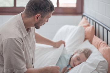 Fototapeta premium Father singing his daughter to sleep, providing comfort, support, and security. Focusing on fulfilling both physical and emotional needs. Kids sometimes act happy while pretending to fall asleep.