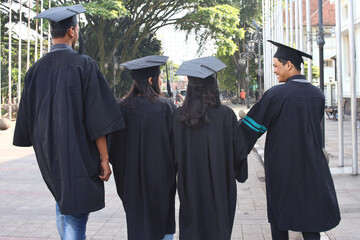 Backside view of group of graduate students walking together after celebrating bachelor graduation