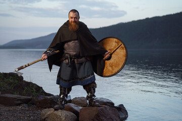 Medieval warrior viking barbarian with ax and shield on shore - 615288578