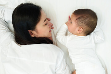 happy mother and infant baby lying on bed