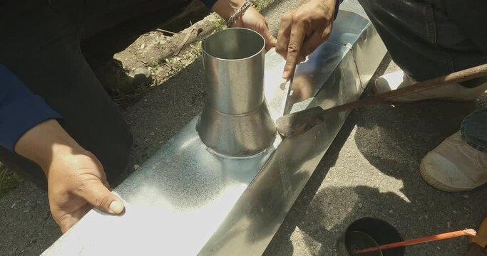Zinc rain gutter welding by using soldering copper. Technician is welding aluminum pipe by using soldering copper.