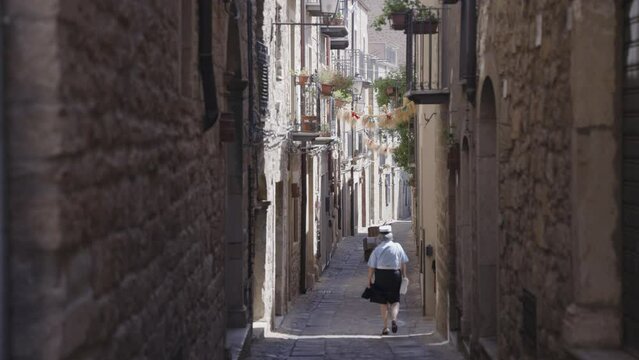 A lady walking though alley of Southern Italian regional village of Gangi, views of Madonie mounts in the province of Palermo Sicily Italy
