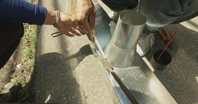 Zinc rain gutter welding by using soldering copper. Technician is welding aluminum pipe by using soldering copper.