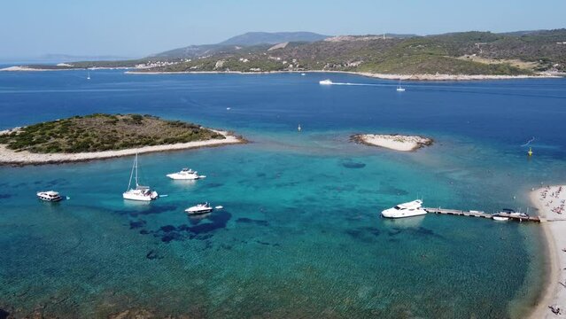 People relaxing at blue Lagoon of Veliki Budikovac Island with Catamarans, Yachts and Boats anchored in crystal clear Bay. Aerial