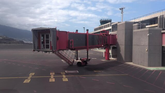 passenger boarding bridge jet bridge moving away from plane in La Palma international airport during sunny morning finger