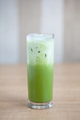 Green tea Matcha with milk and ice in round glass isolated on white with shadow and light. Cold drink famous for detox and healthy beverage in Japan and Korea and Asia melting under sun hot weather.
