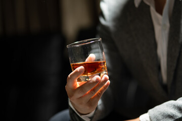 Businessman sitting Holding a Glass of Whiskey Drink Whiskey in the liquor store room