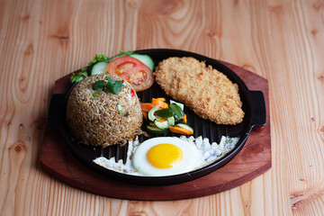 Fried Rice with Chicken. Prepared and served in a Plate. Natural wood in the background. Top view.