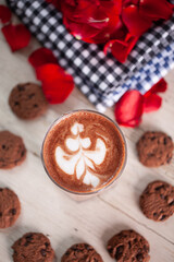 Hot Chocolate drink with latte art on wooden table and roses decoration. Flat lay