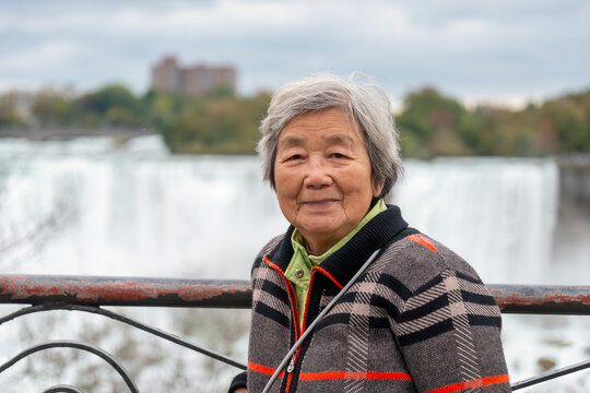 Senior Chinese tourist posing for photos at Niagara Falls, Ontario. Canada.
