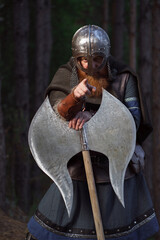 Fantasy medieval red-haired gnome warrior with beard with huge ax halberd in forest