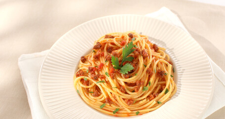 spaghetti bolognese on a white plate. classic italian pasta with meat tomato sauce on a light background. dish of mediterranean cuisine. food on the table on a sunny day. yellow noodles, minced meat.