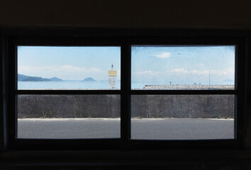 古いバス停の窓から島の漁港を望む / 山口県大島郡周防大島町
