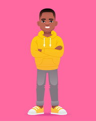A black little boy stands with his arms folded. Cute african school kid in yellow hoodie.