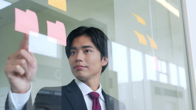 オフィスで付箋を見ながら考えるビジネスマン