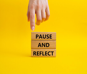 Pause and Reflect symbol. Concept words Pause and Reflect on wooden blocks. Beautiful yellow...