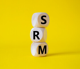 SRM - Sustainability Risk Management symbol. Wooden cubes with word SRM. Beautiful yellow background. Business and Finace and SRM concept. Copy space.