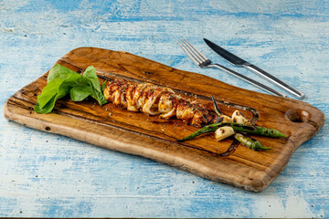 Spicy sliced grilled squid with green pepper and garlic on a wooden serving board