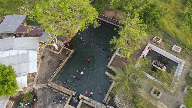 Aerial view of people in natural swimming pool in the midle of forest in Klaten, Indonesia
