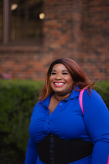 Fototapeta premium A beautiful young woman lets out a big laugh. She is on a college campus, and dressed in casual professional wear. Adding more backstory, she is African American.