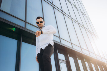 business man stands near the houses..male portrait on the background of buildings.business man portrait. Man stands near business center. office worker.male portrait.man near skyscrapers.businessman.