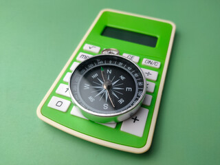 Closeup green calculator with compass on a green background