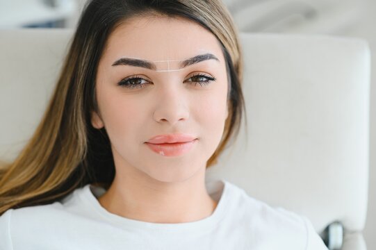 Young woman during professional eyebrow mapping procedure.
