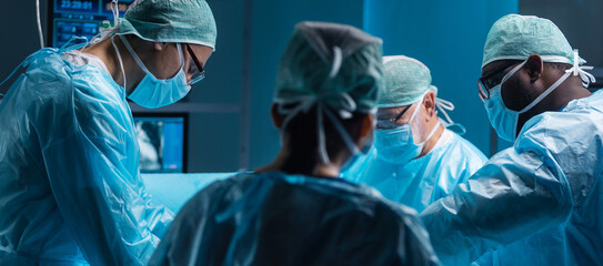 Team of medical doctors performs surgical operation in modern operating room using high-tech...