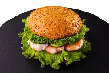 Burger with sesame bun, shrimps, fresh green salad and cucumbers.