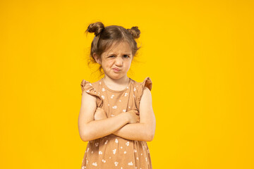 Displeased little girl on a yellow background - obrazy, fototapety, plakaty