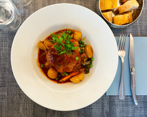 Delicious braised duck leg with potato, carrot and green peas, french cuisine