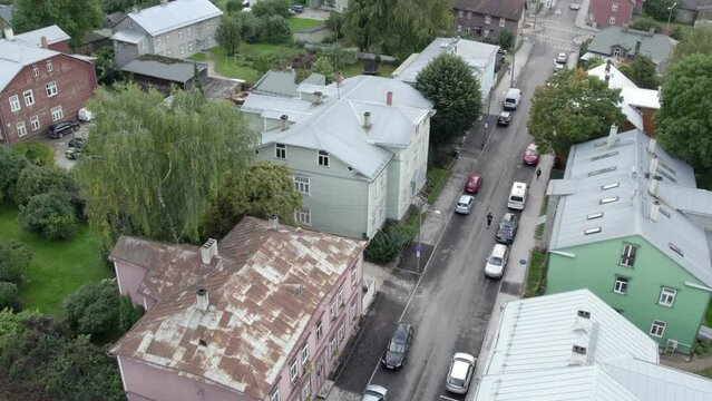drone recording from air how man on scooter driving middle of road in karlova between old wooden houses on Eha street