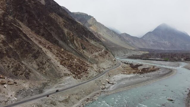 Aerial drone forward moving shot of winding KKH road over picturesque Karimabad Hunza Valley with Rakaposhi mountains in the background in Hunza, Balochistan.