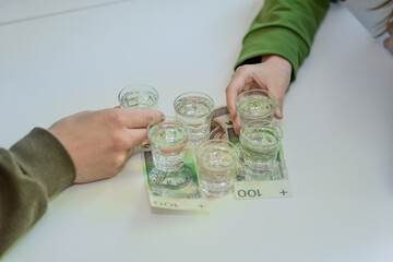 Spożywanie alkoholu w kieliszkach stojących na polskich banknotach  - obrazy, fototapety, plakaty